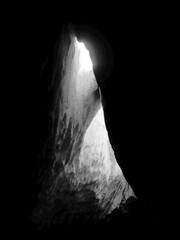 black and white image of a natural formation in a cave looking like a bright illuminated entrance