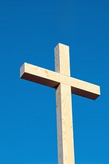 Wooden cross stands against a vibrant blue sky.