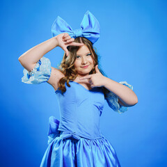 Cute teenage girl in blue doll dress with big blue bow posing.