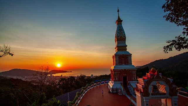 Time lapse A stunning sunset view over a traditional Thai temple perched on a hill, with a colorful glow over the ornate architecture and distant Patong gulf. the natural beauty of the scene.