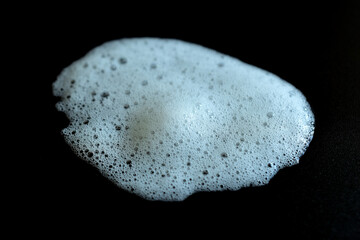 Close-up of air bubbles in soap foam on black background.