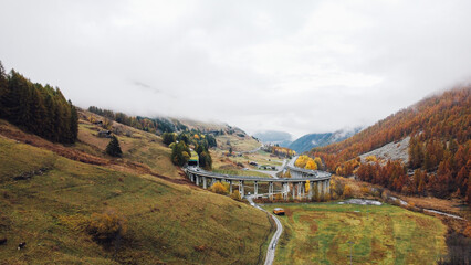 Mountain landscape in the Aosta valley near the Great St Bernard Tunnel. Aerial view of misty slopes and autumn forest in the Alps.
