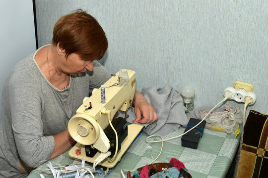 Seamstress working at a sewing machine. Close-up. Side view.