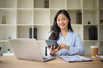 Professional female bookkeeper reviewing financial data and calculating figures.