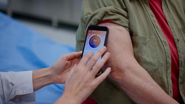 Endocrinologist teaching older patient how to connect continuous glucose monitor with mobil app.