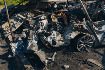 Burnt carcasses covered in ash and mud show twisted metal and melted structures. Destroyed car...