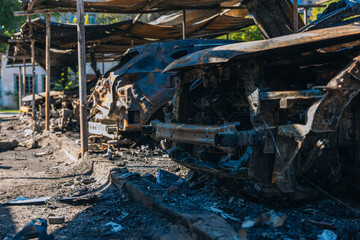 Burnt carcasses covered in ash and mud show twisted metal and melted structures. Destroyed car...