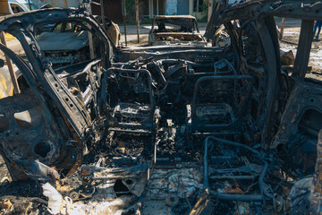 Burnt carcasses covered in ash and mud show twisted metal and melted structures. Destroyed car...