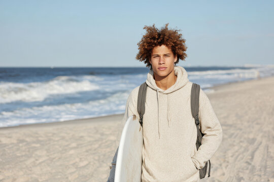 teenager wearing cozy hoodie and carrying backpack stands confidently on beach radiating energy