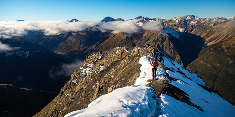 Brave hiker girl crosses narrow snow covered ridge on way to Avalanche Peak summit. Breathtaking...