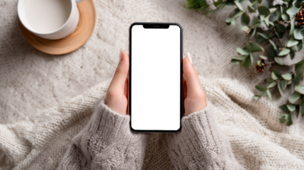 Woman holding blank smartphone screen mockup in cozy sweater lifestyle setting
