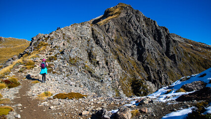Brave hiker girl climbs steep rocky vertical wall on way to Avalanche Peak summit, Arthur's Pass National Park, Canterbury, South Island, New Zealand