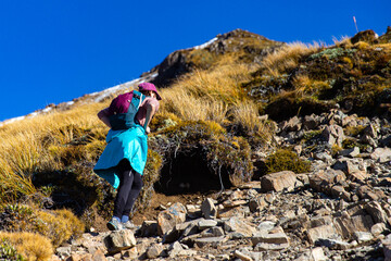 Brave hiker girl climbs steep rocky vertical wall on way to Avalanche Peak summit, Arthur's Pass National Park, Canterbury, South Island, New Zealand