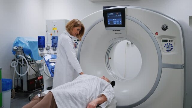 Doctor operating dynamic X-ray scan using tilting fluoroscopy unit.