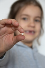 A little girl happily shows off her first lost tooth on camera
