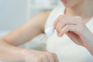 Beautiful Asian woman smile and test serum for good skin. face of a healthy woman apply cream and makeup. Advertisement for skin cream, anti-wrinkle, baby face, whitening, moisturizer