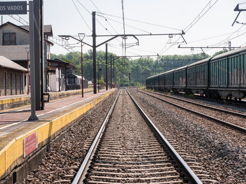 Toral de los Vados, Leon, Spain, 06-16-2025: Main track of the station between the passenger building and some parked cars and a high signal in the background with the red light on indicating a stop