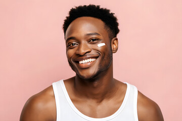 Smiling Black man with cream on cheek and pink background