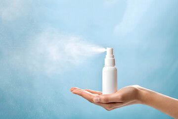 White spray bottle misting from hand on blue background