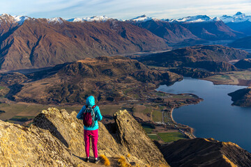 Adventurous hiker girl stands on summit of Roys Peak admiring breathtaking panoramic view over Lake...
