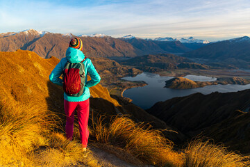 Adventurous hiker girl stands on summit of Roys Peak admiring breathtaking panoramic view over Lake...