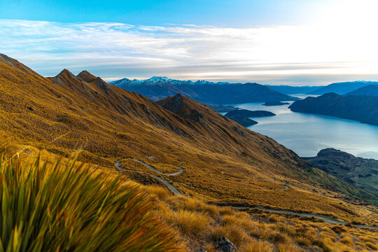 Stunning panoramic sunrise view from Roys Peak summit overlooking Lake Wanaka and surrounding snow covered peaks near Wanaka, Otago, South Island, New Zealand