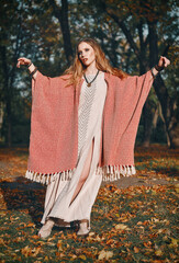 Outdoor fashion: portrait of the sweet young boho (hippie) girl in forest. Charming hippy woman dancing in grove at sunset time