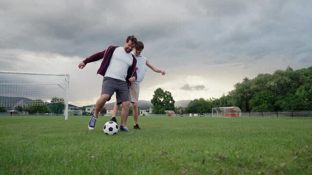 Happy father and son having fun during football game, enjoying quality time together.