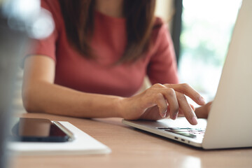 Woman working remotely, using laptop computer, surfing the internet at coffee shop. online job,...