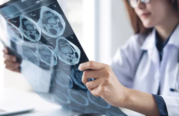  Asian orthopedics surgeon doctor examining patient's knee joint x-ray films, MRI bone, ct scan in radiology orthopedic unit in hospital. knee joint film x ray, close up © tippapatt