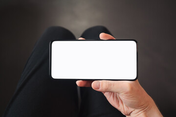 pov shot of man hand hold phone with white screen in dark interior