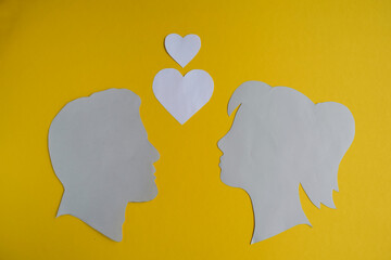 Male and Female Silhouettes with Two Hearts on Yellow Background