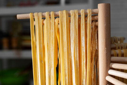 Homemade noodles hanging on wooden dryer rack closeup low angle view - Powered by Adobe