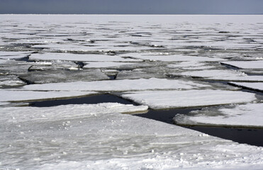 Frozen sea with large ice floes breaking apart, forming a mosaic-like pattern on the surface. A striking winter landscape in a cold Arctic climate.