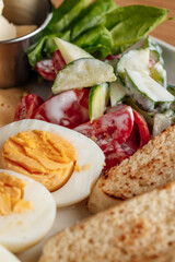Close-up of a healthy breakfast plate with hard-boiled eggs, fresh cucumber and tomato salad with yogurt dressing, and golden toast slices.