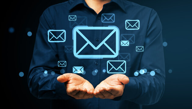 Businessman presenting floating email icons in digital network communication concept on dark background with glowing blue elements.