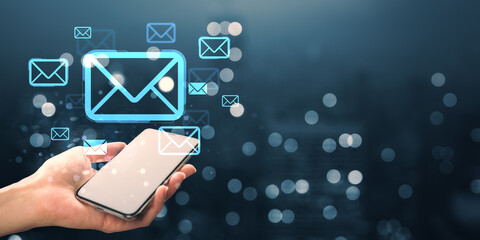 Digital communication concept with email icons floating above smartphone screen in hand on dark blurred background with bokeh lights.