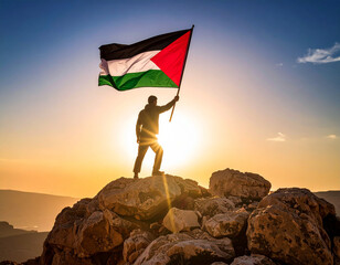 A person stands atop a rugged mountain peak, proudly waving a large Palestinian flag toward a sweeping valley bathed in golden light framed by dramatic clouds and a vivid blue-orange sky