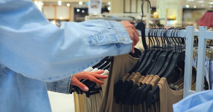 Woman browsing beige tank tops on rack, tank focus repeated to highlight fit, tank strap framing casual summer style moment in airy store setting emphasizing comfort and color coordinate