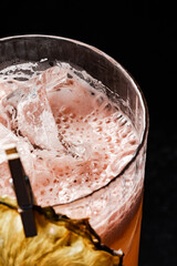 Close-up of a refreshing citrus drink with ice cubes and a frothy foam top in a textured glass,...