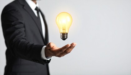 3D scene with a lightbulb-shaped idea icon floating above the hand of a blurred man in a suit