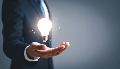 3D scene with a lightbulb-shaped idea icon floating above the hand of a blurred man in a suit