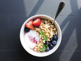 Healthy breakfast bowl with yogurt, granola, berries, and mint, copy space
