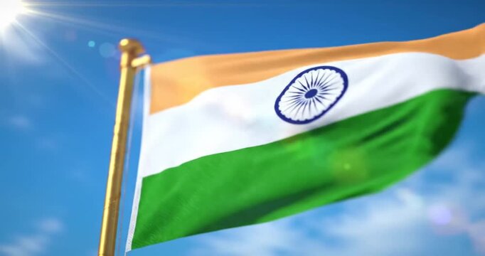 The Indian flag with a gold pole flutters majestically under the blue sky.
