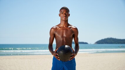 Athletic african american man training with medicine ball on beach fitness workout