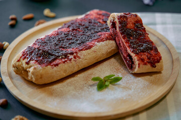 Delicious Homemade Fruit Jam Roll Cake Perfectly Sliced and Served on a Wooden Board with Fresh...
