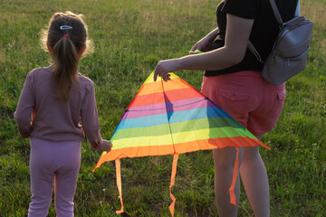 A young mother and her little daughter fly a kite.
