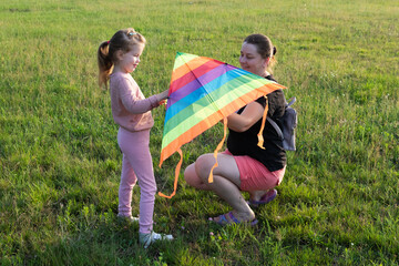 A young mother and her little daughter fly a kite.