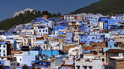 Overhead view of blue and white buildings on the side of a hill, in the medina in Chefchaouen, Morocco