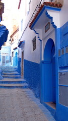 Doors off an alley with blue and white walls, and steps, in the medina in Chefchaouen, Morocco